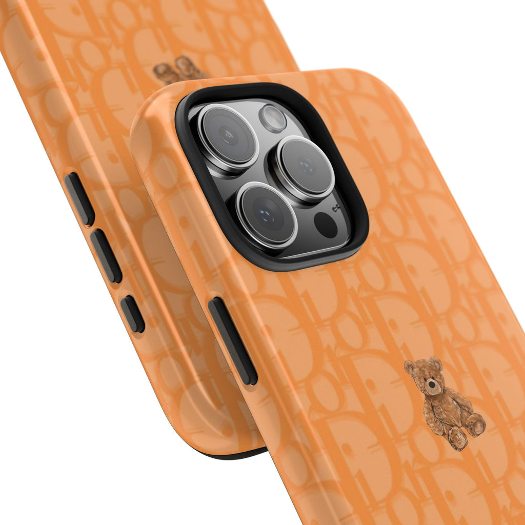 Orange phone case with Dior pattern and teddy bear patch; side button openings visible.