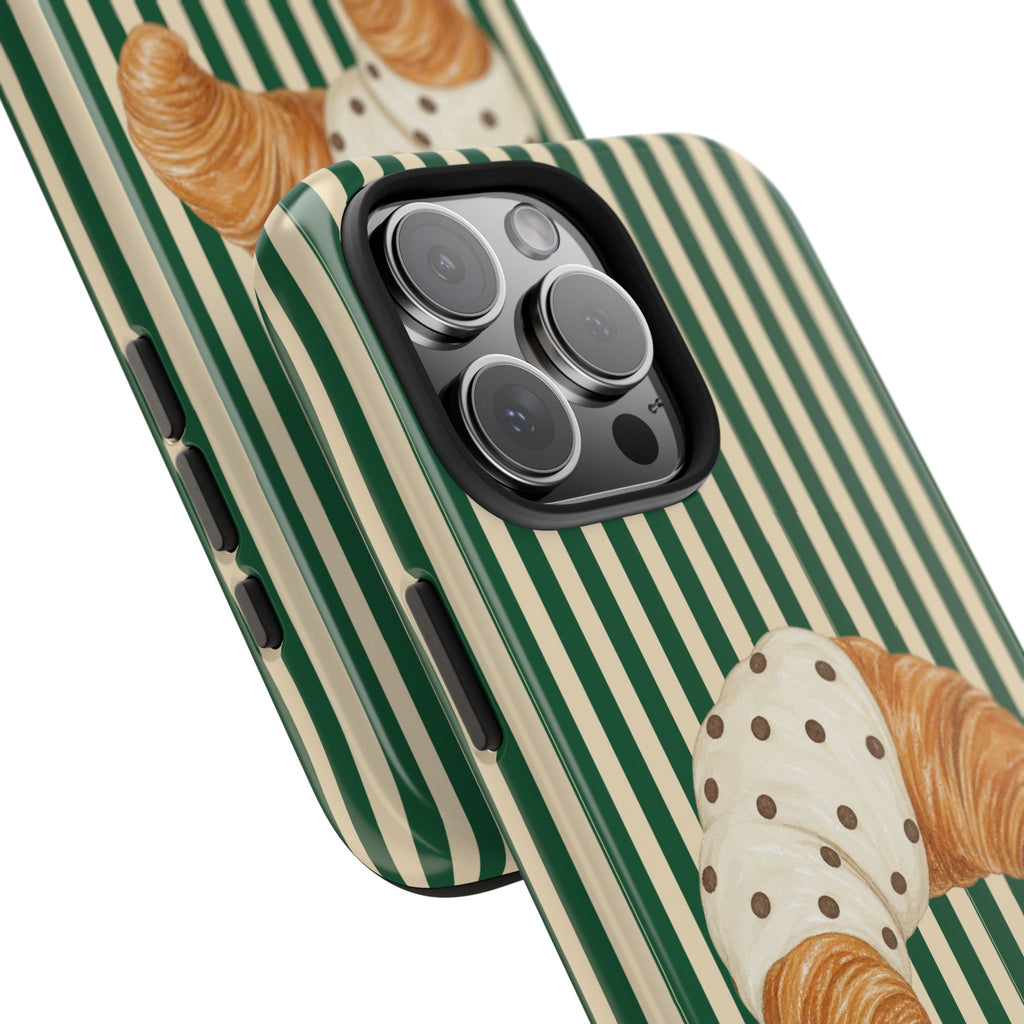 Phone case closeup: green-and-cream striped design with croissant graphic near camera lenses