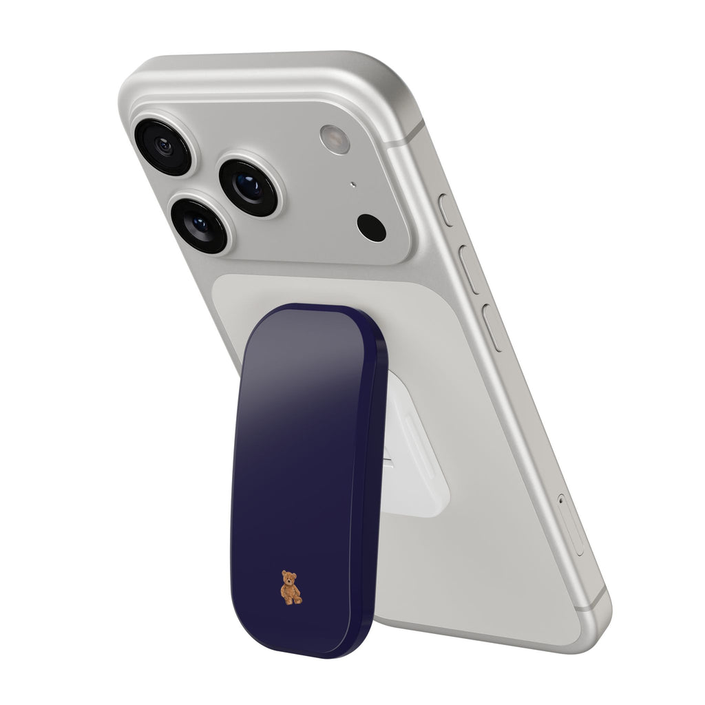White phone case with navy grip and small teddy bear patch near bottom