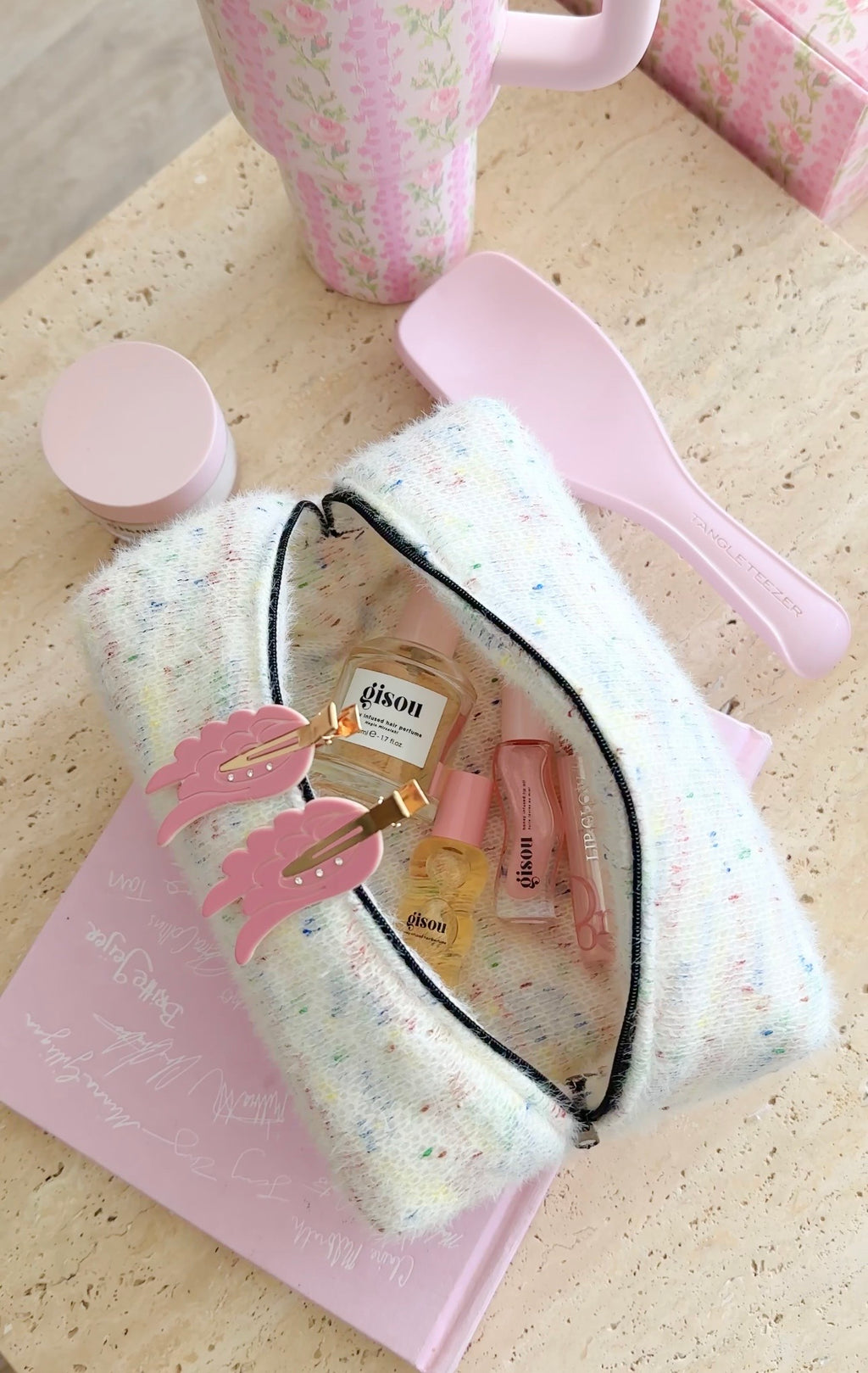Pastel confetti-patterned pouch with black zipper, open with vanity items inside