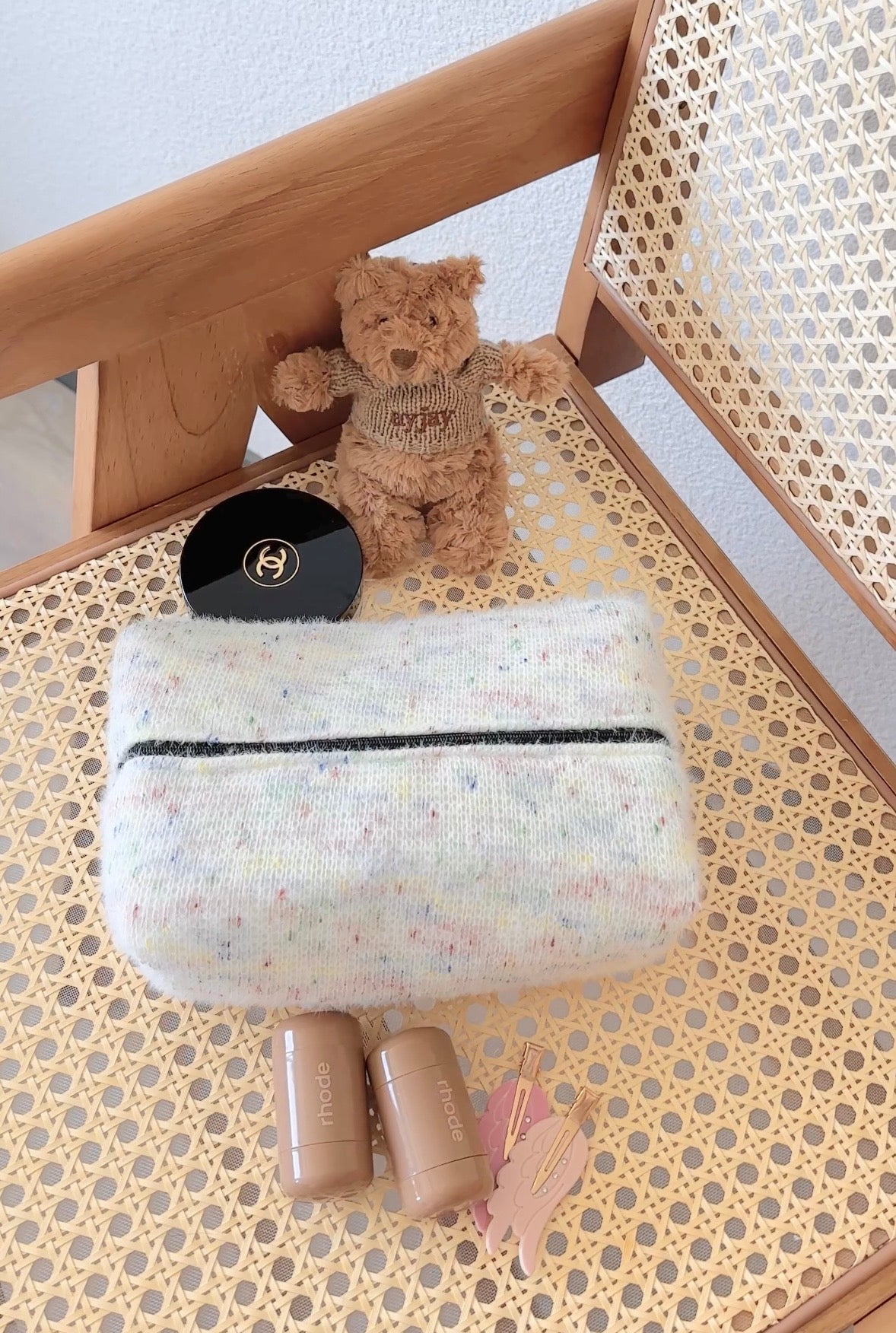 Light confetti pouch with black zipper, folded-open in a wooden organizer