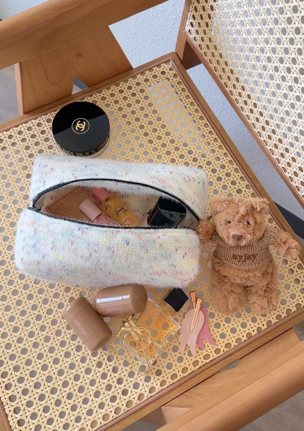 Confetti-patterned pouch with black zipper, open with cosmetics and mirror inside