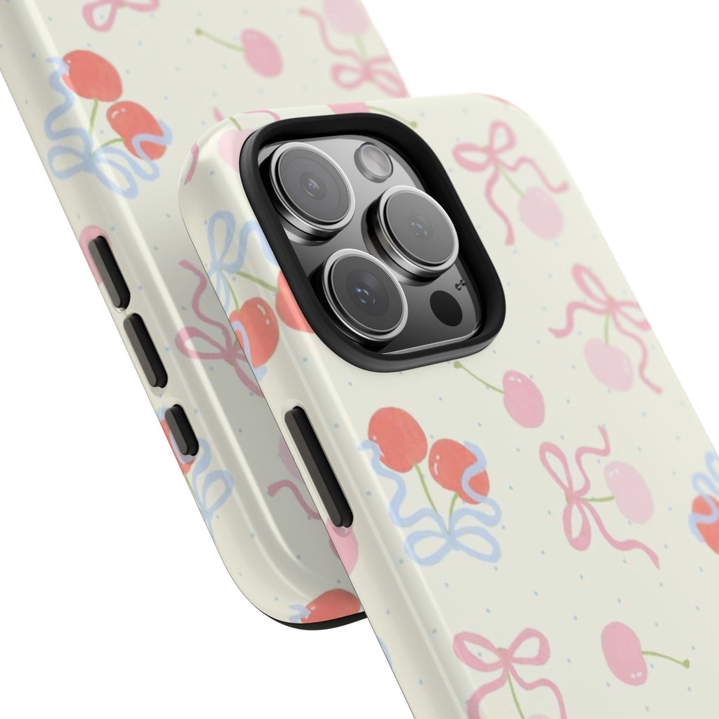 Cherry-print phone case, off-white with pink/blue bows; raised lenses and side buttons