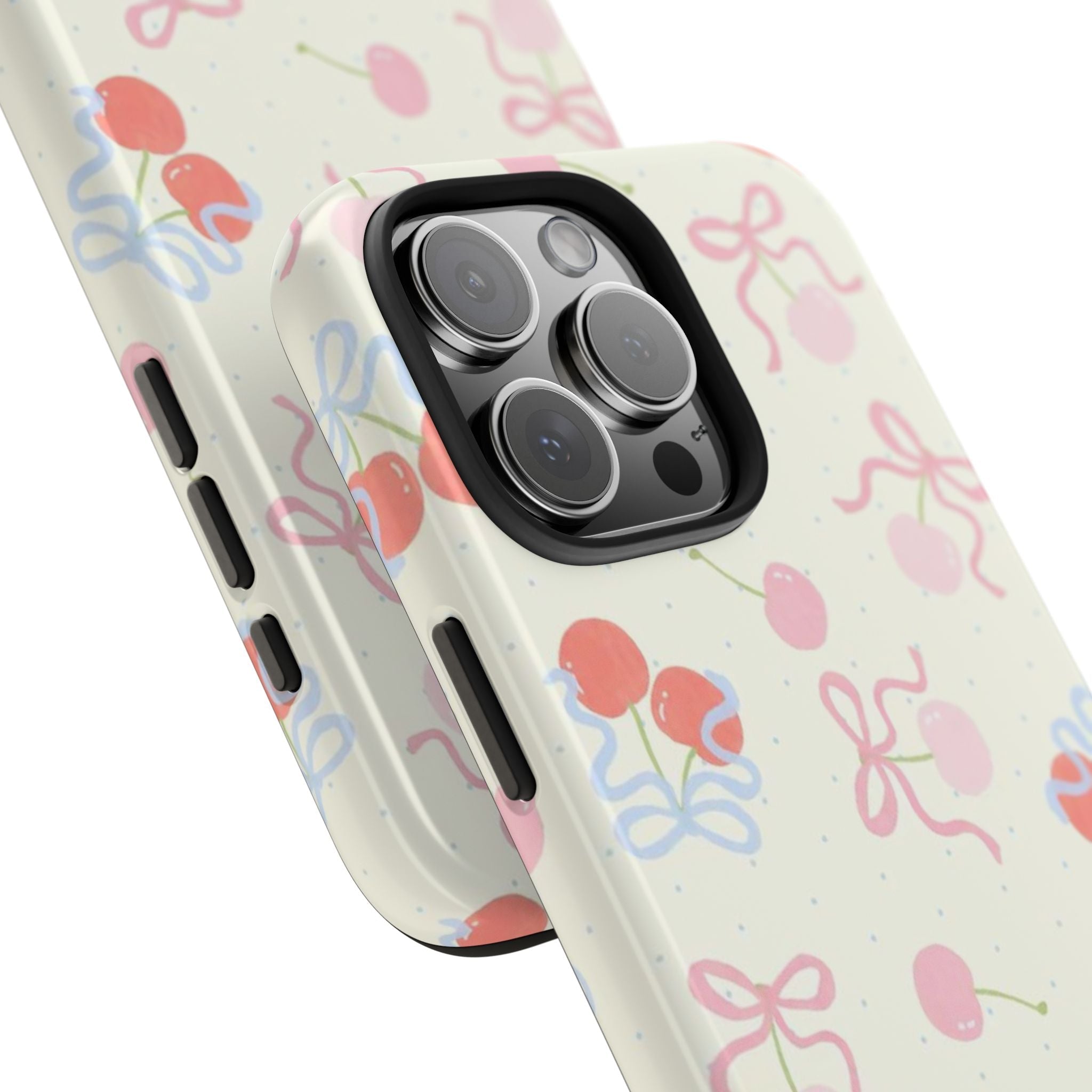 Cherry-print phone case, off-white with pink/blue bows; raised lenses and side buttons