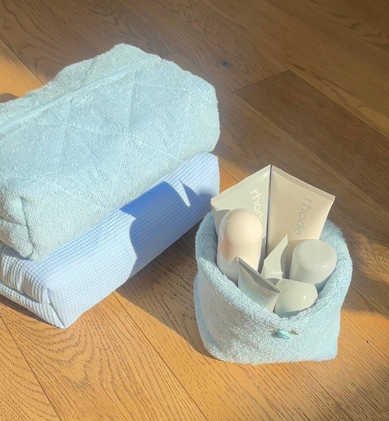 Light blue terrycloth organizer basket with folded towel and white toiletries