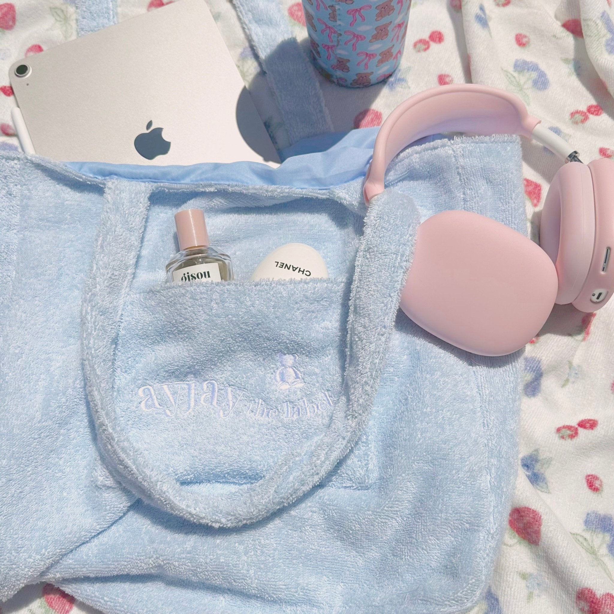 Close view of baby blue terrycloth tote bag front pocket with embroidered logo