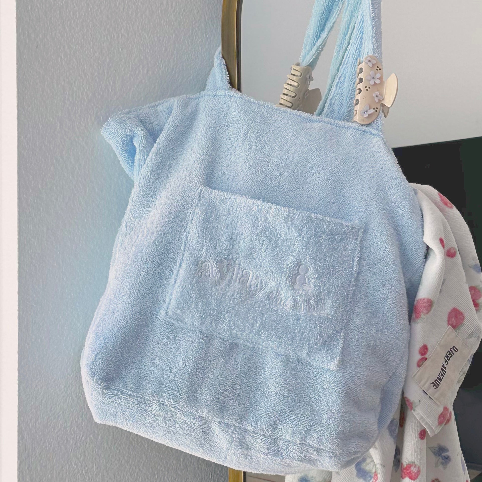 Baby blue terrycloth tote bag with wide handles and embossed front logo