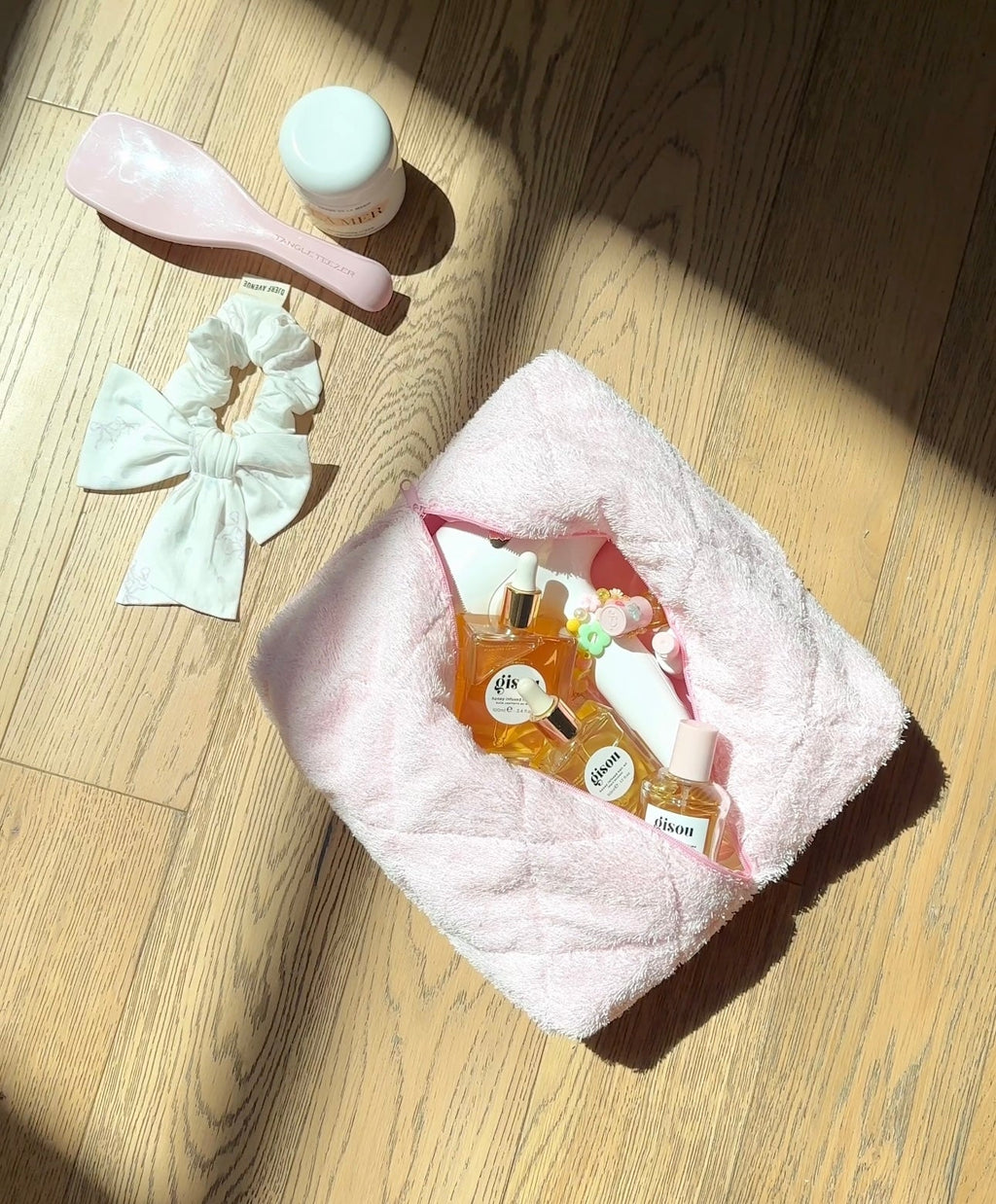 Baby pink terrycloth towel folded on floor, visible terry texture and curved edge