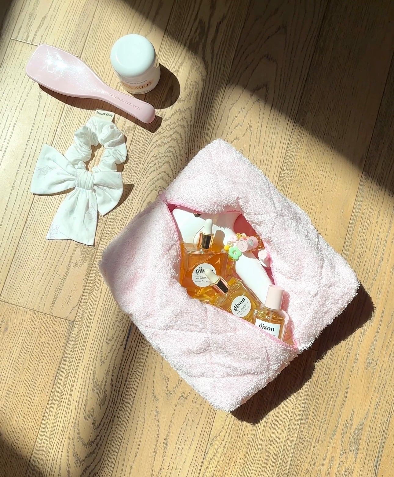 Baby pink terrycloth towel folded on floor, visible terry texture and curved edge