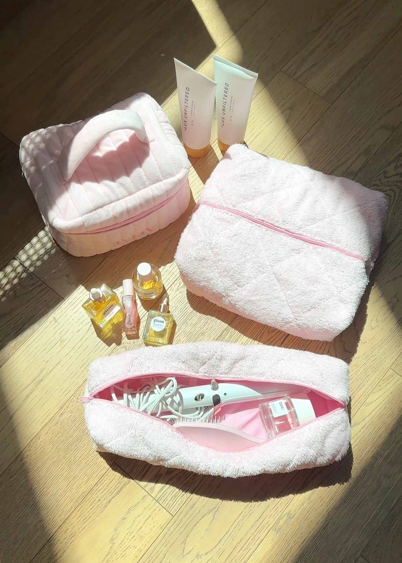 Pink teddy-style zip pouch with quilted exterior and pink trim, closed hair-tool bag