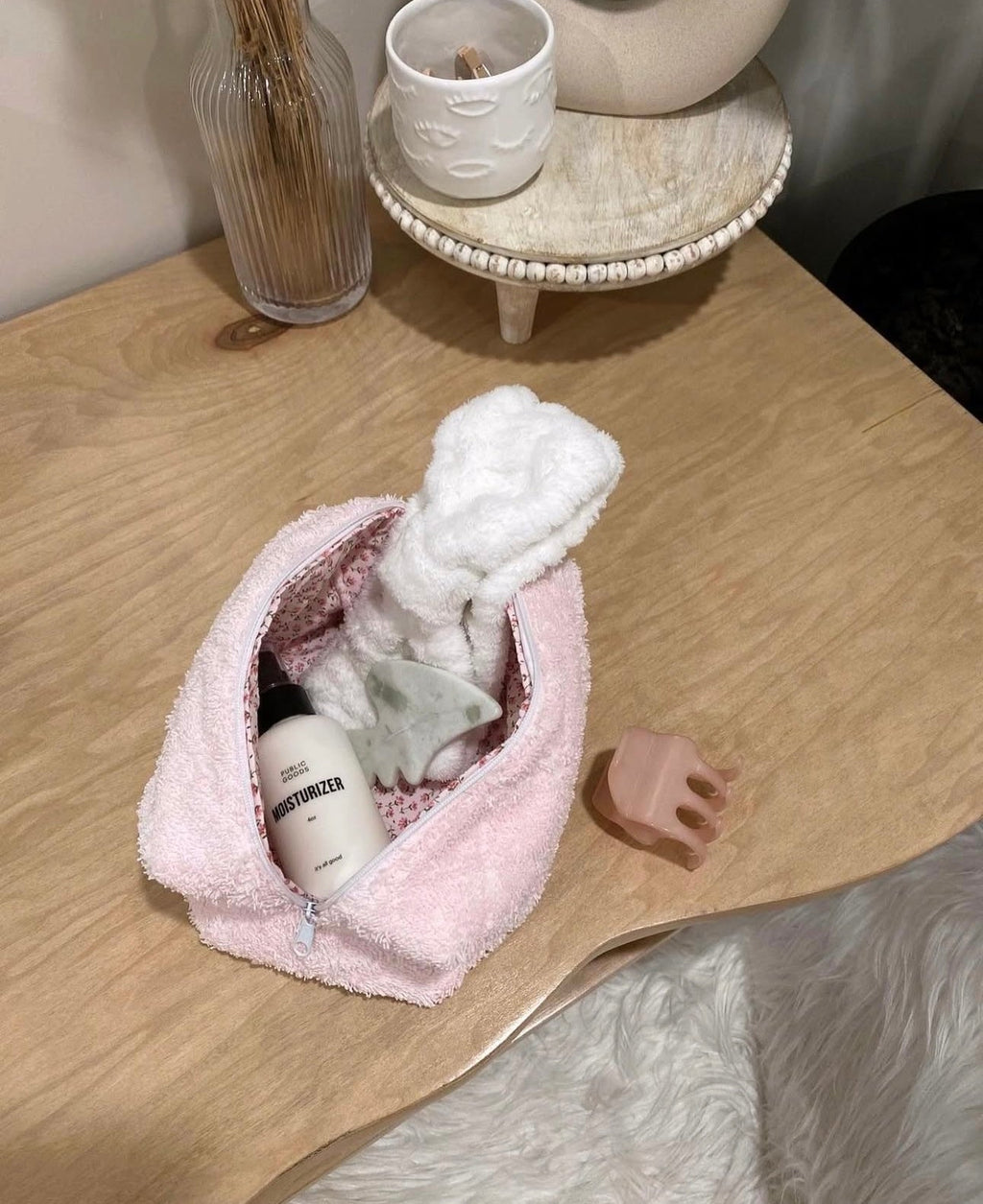Pink teddy makeup bag with zipper open; holds small bottles and toiletries