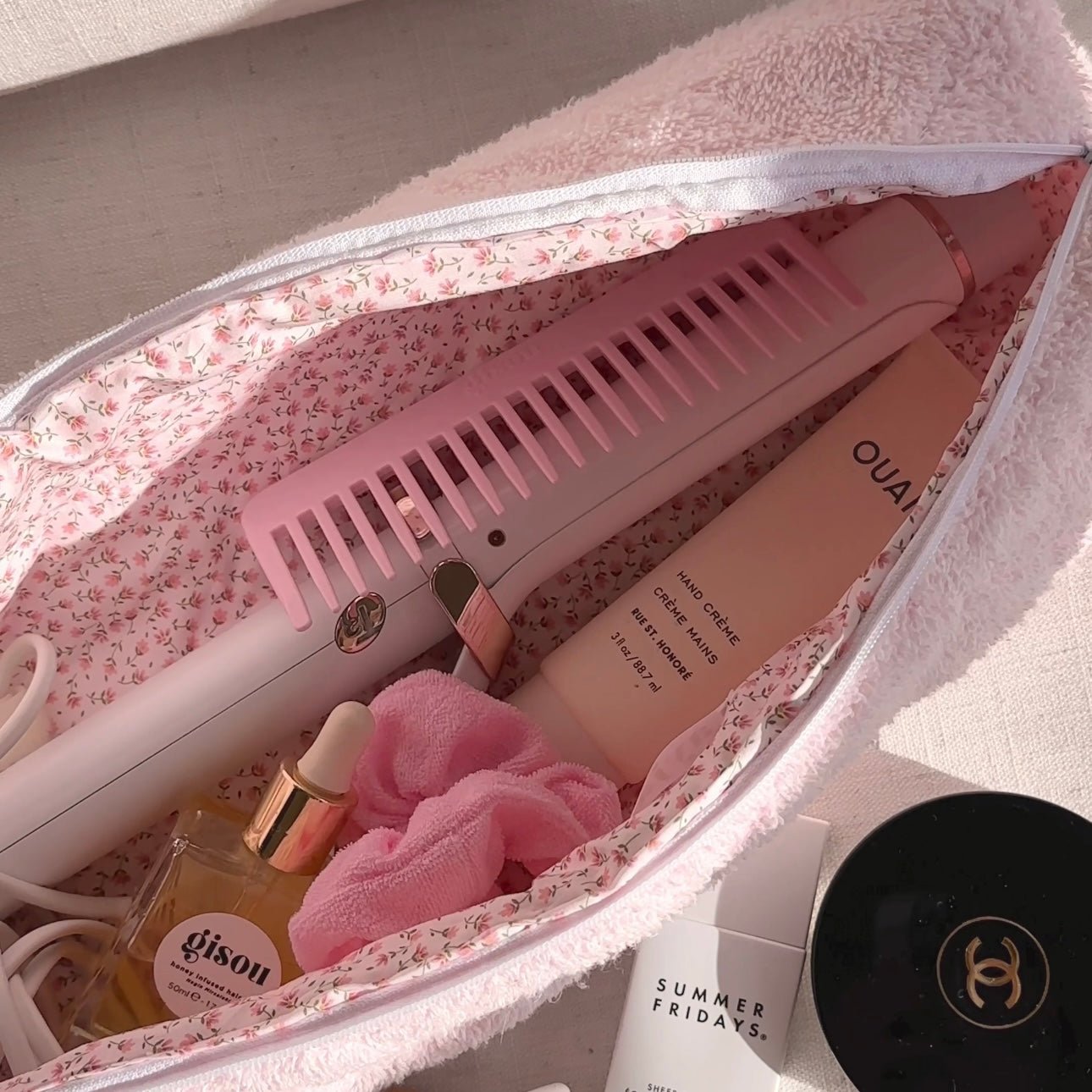 Baby pink terrycloth zip pouch open, comb slots and floral lining with accessories