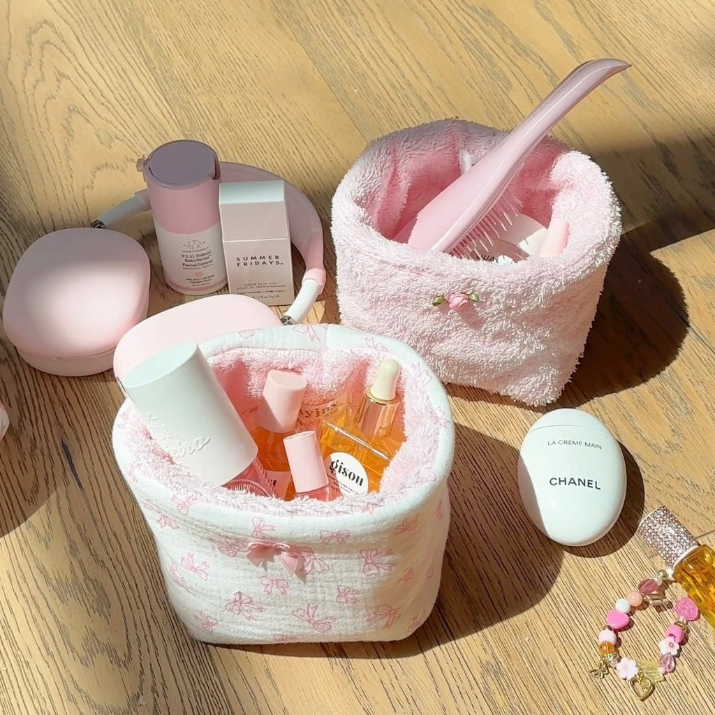 Baby pink terrycloth organizer bin with curved handle and open top, toiletries inside