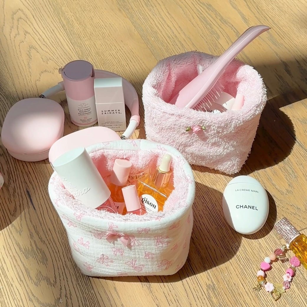 Baby pink terrycloth organizer bin with curved handle and open top, toiletries inside