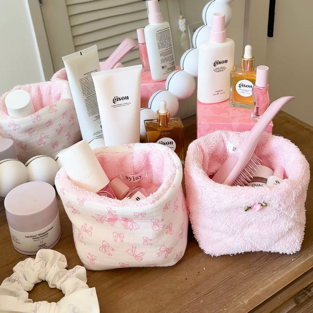 Pink terrycloth organizer bin with bow-pattern outer, open top with toiletries inside