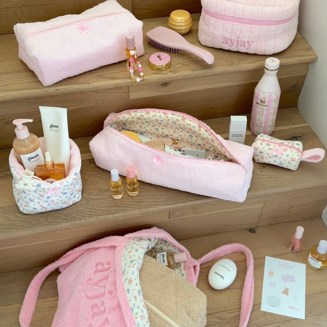 Pink terrycloth toiletry pouch with floral lining, zip top, and bow accents