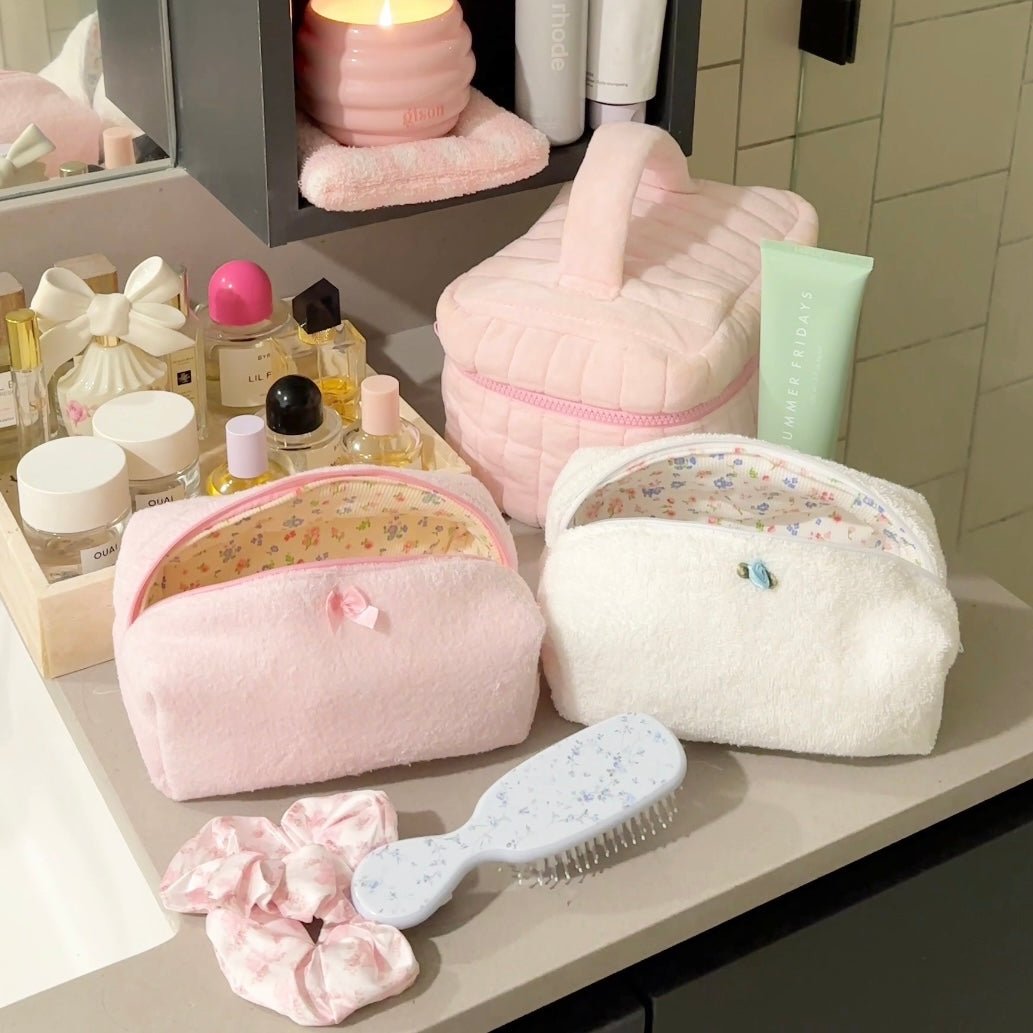 Pink and white terrycloth zip pouches with floral lining, bow, and trim