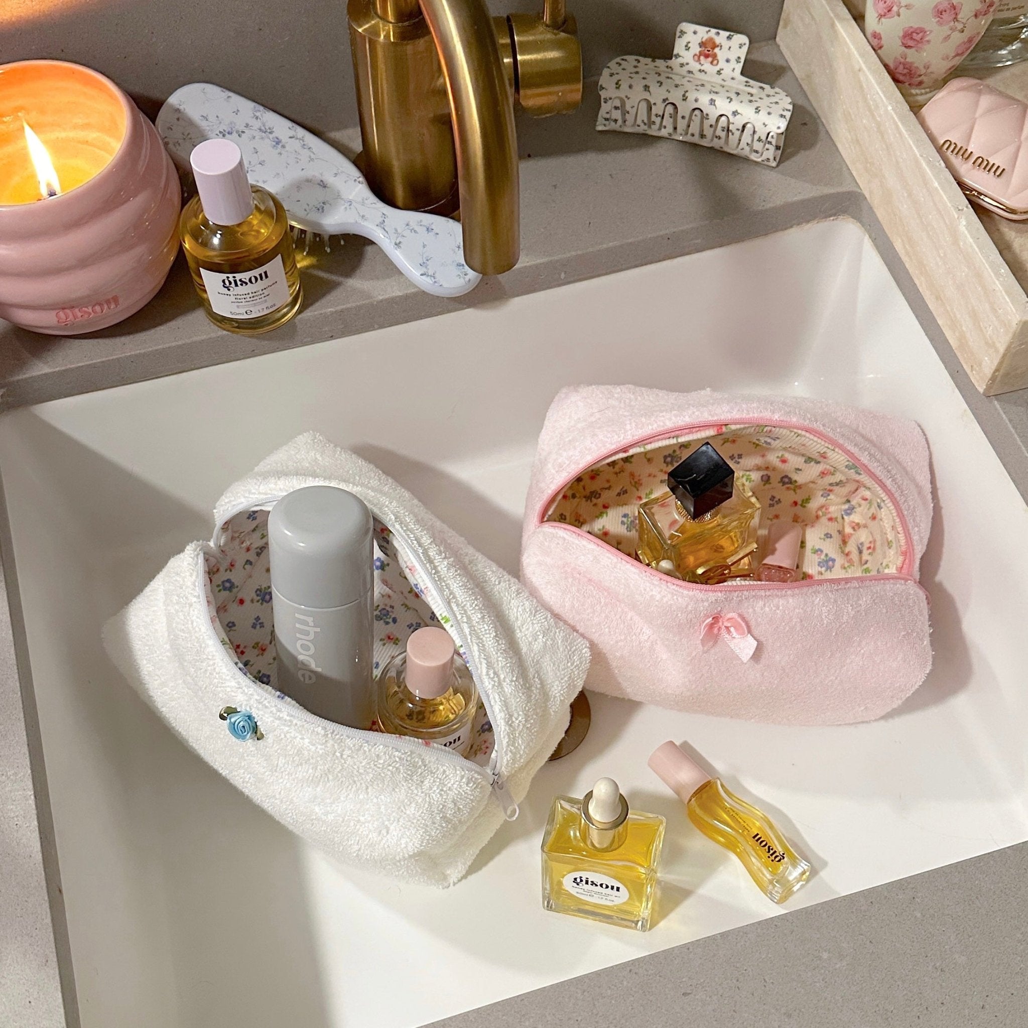Light pink terrycloth zip pouch with floral interior, bow, and zipper pull