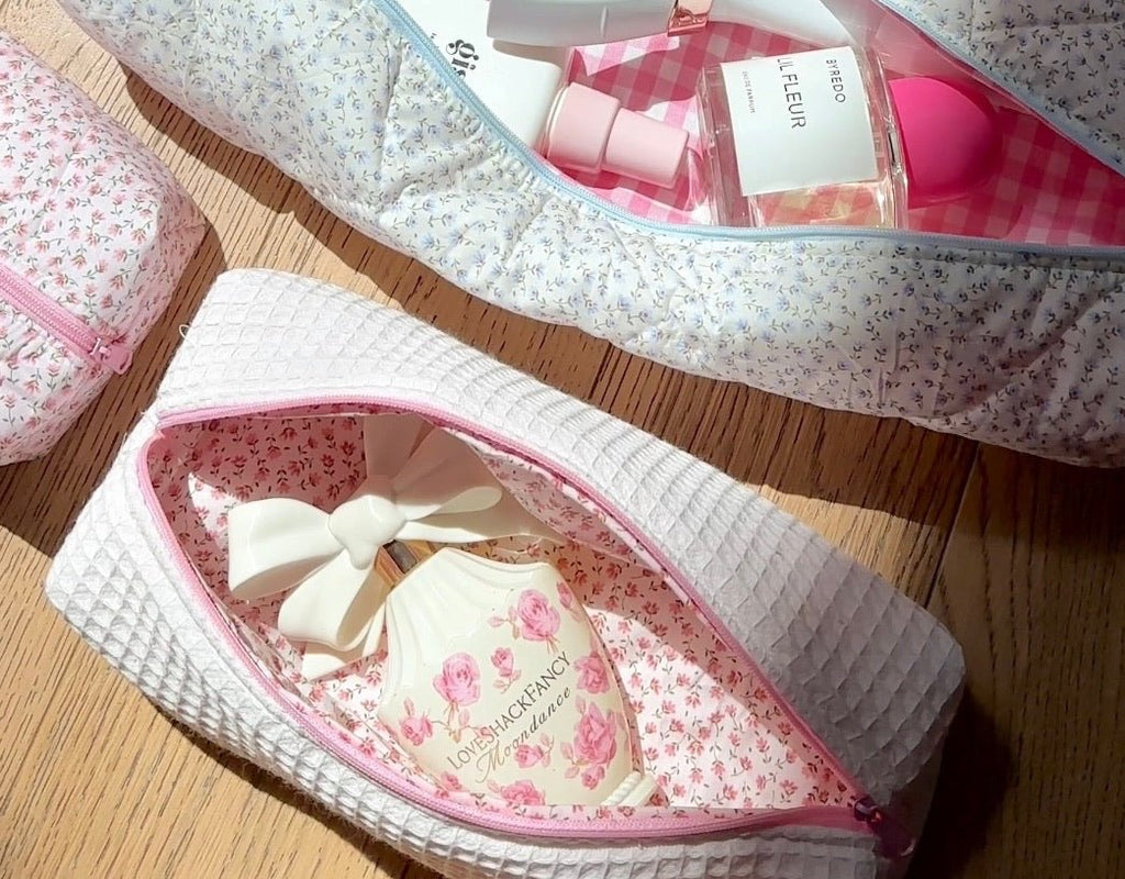 White waffle-knit cosmetic pouch with pink zipper, open floral interior and bow detail