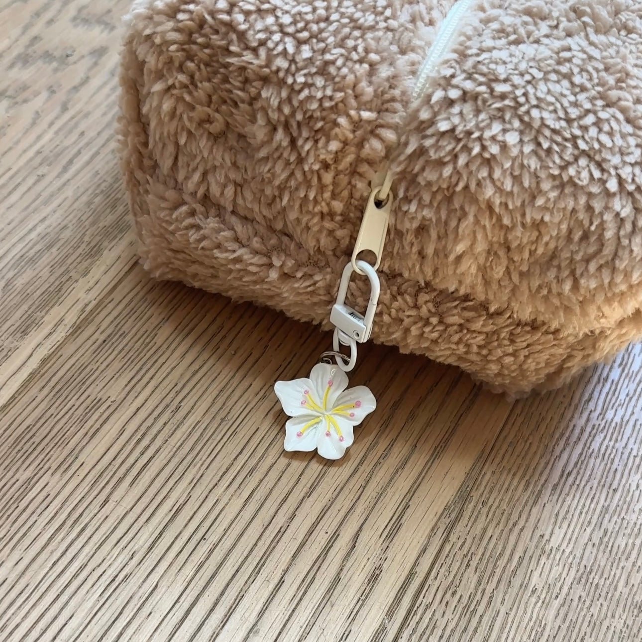 Flower bag charm with white petals and pink/yellow center, on white clip