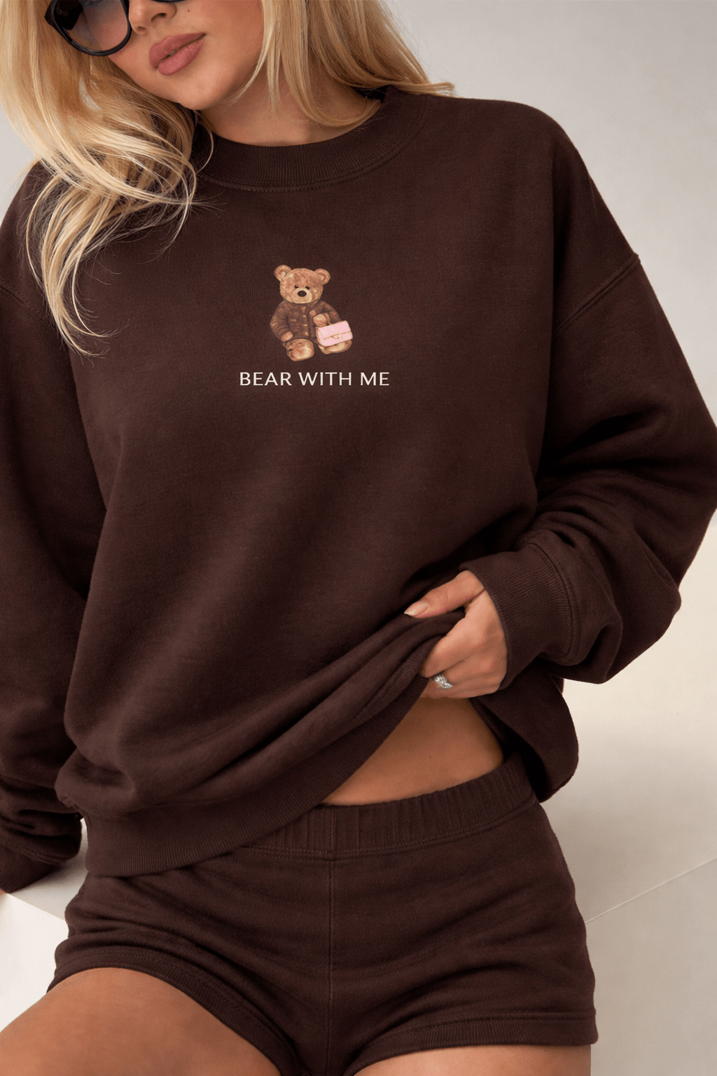 Dark brown crewneck sweatshirt with teddy bear graphic on chest, worn