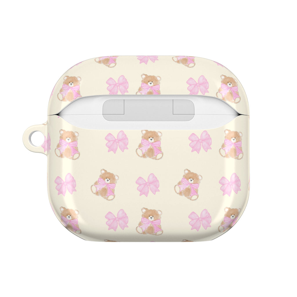 Beige AirPods case with teddy bear and pink bow pattern, charging port opening