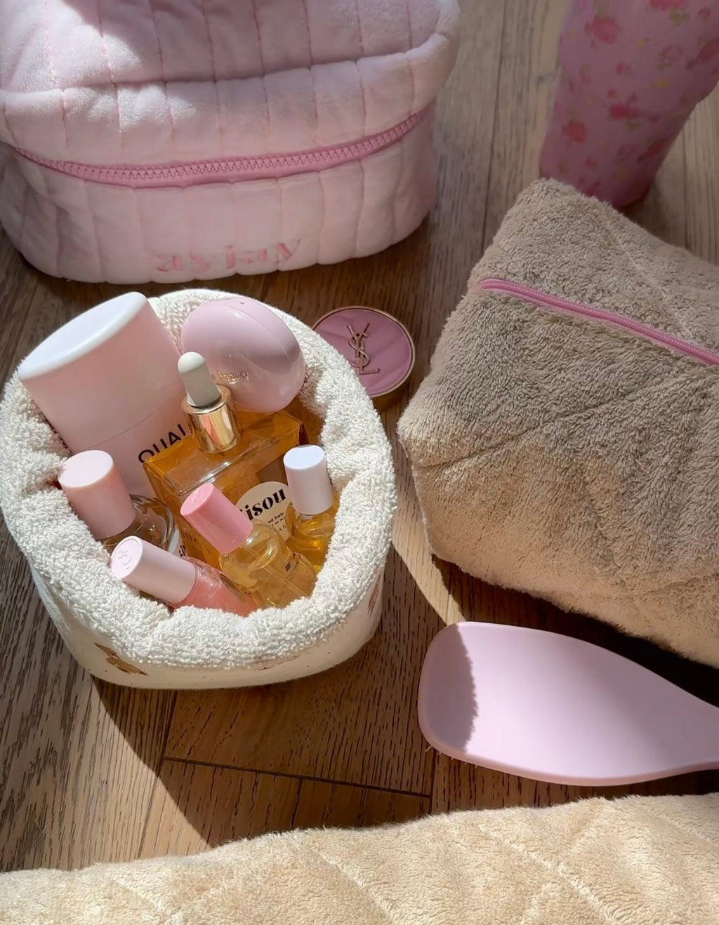 Beige plush organizer pouch with pink zipper opening, teddy-bear applique, holds mini bottles