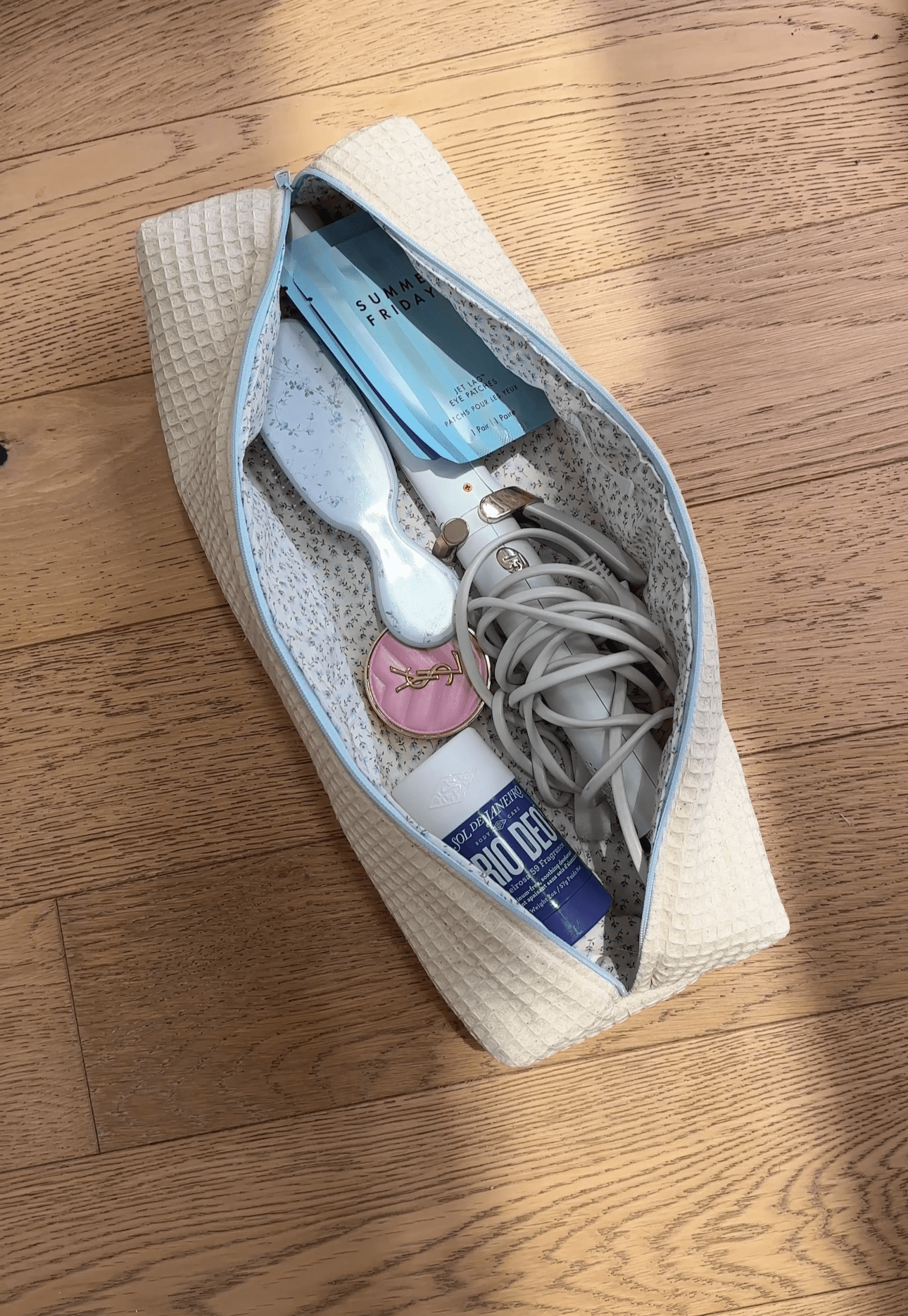 Cream waffle-knit zip pouch with light-blue zipper edge, open with small items inside