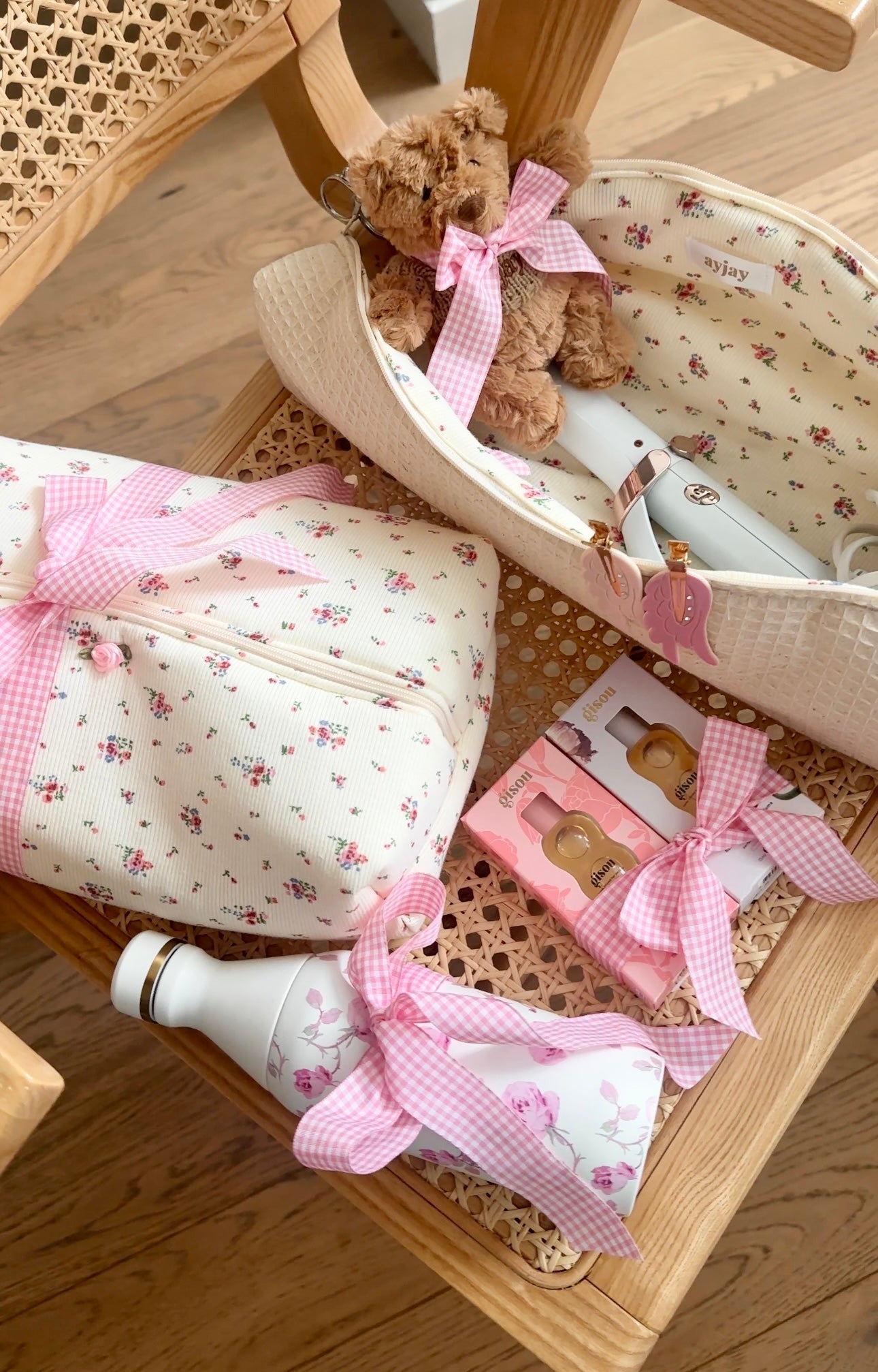 Oval zip pouch with floral lining and pink bow; teddy and baby bottles in tray