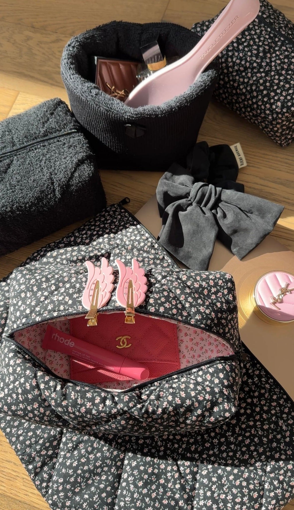 Black ditsy floral toiletry pouch with zipper, open to reveal pink-lined interior