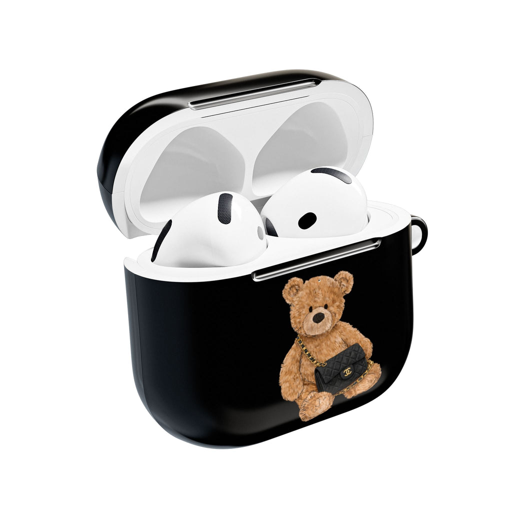 Black flap AirPods case with teddy bear charm; open lid showing white earbuds