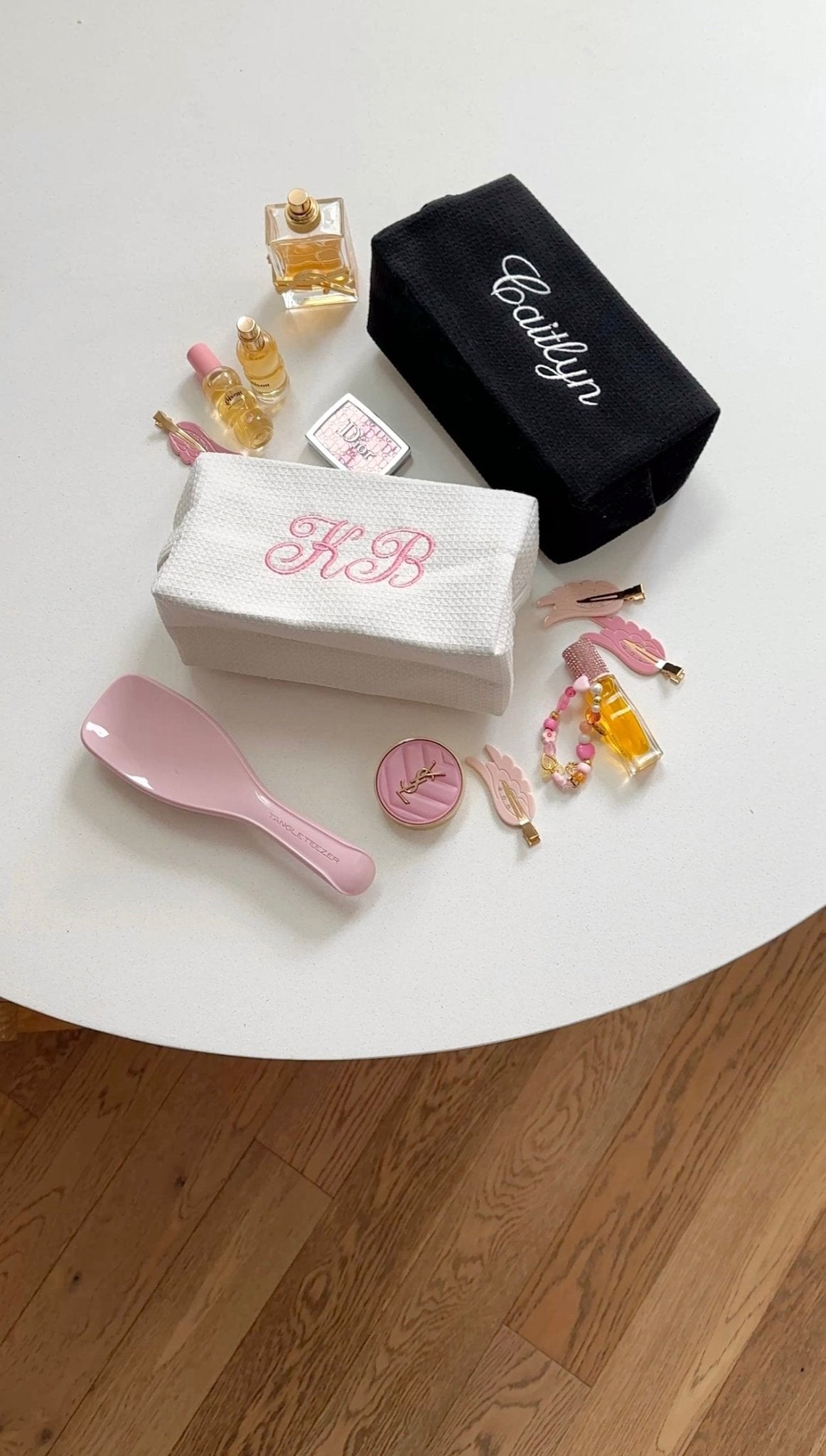 White waffle knit bag with pink 'KB' embroidery; black bag with white 'Caitlyn'