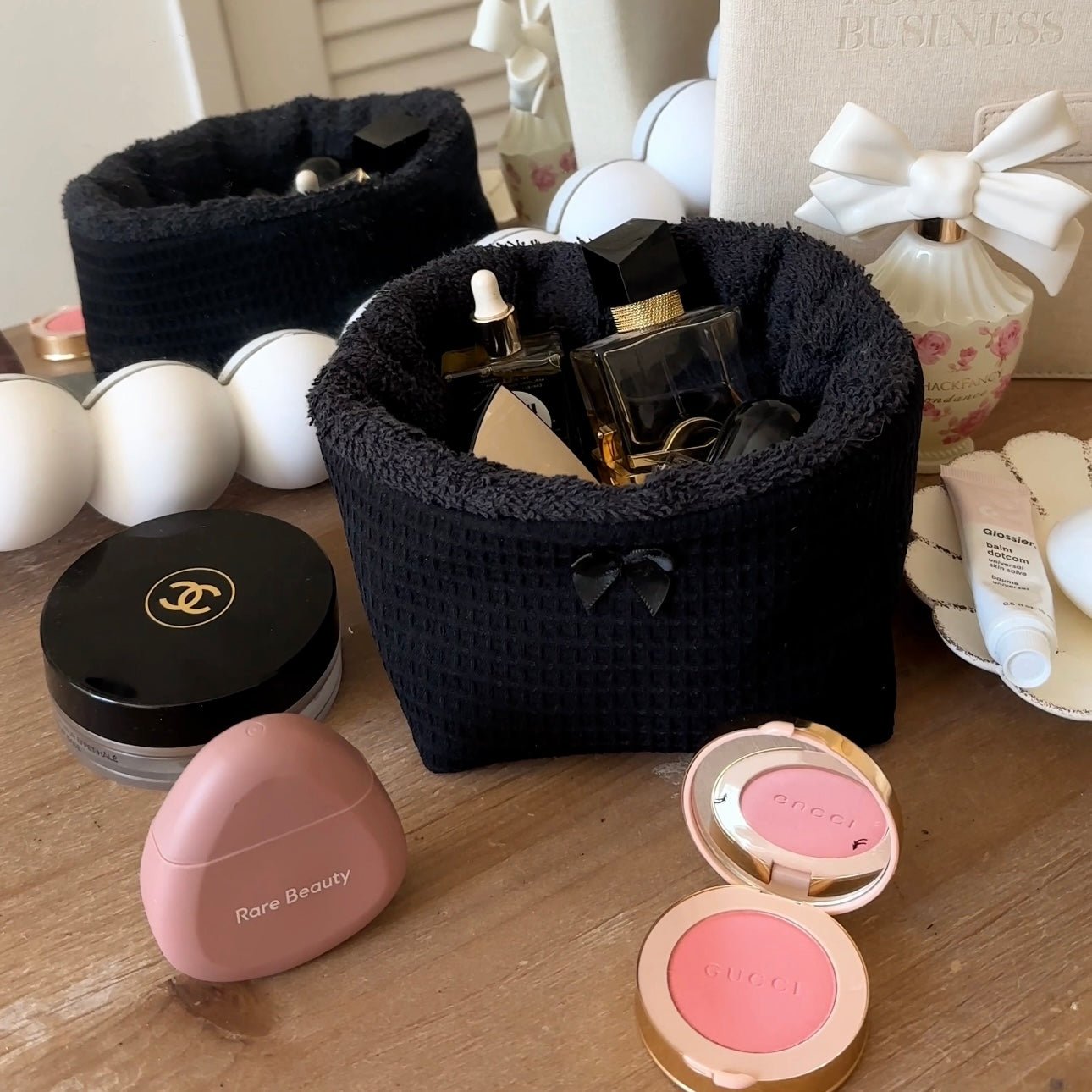 Black waffle-knit organizer basket with plush rim, bow tied handle, vanity bottles