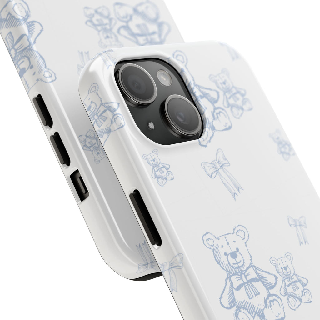 White phone case with blue teddy bear and ribbon pattern, angled near camera lenses