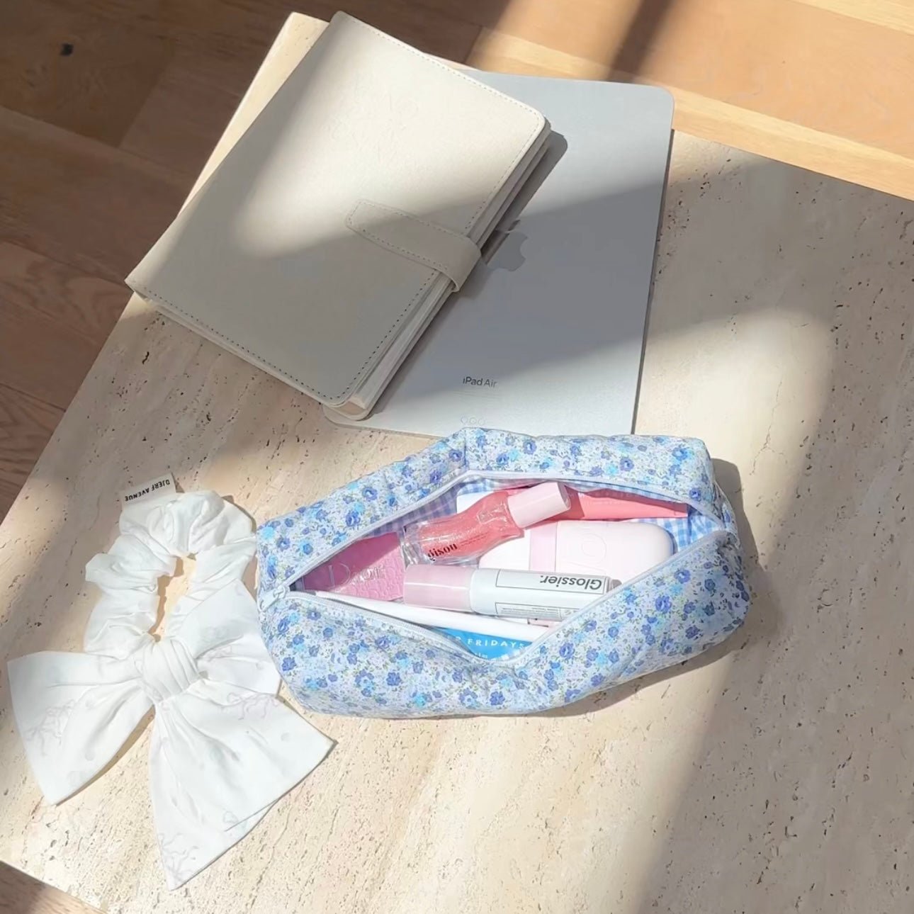 Blue floral zippered pouch open, holding small toiletries