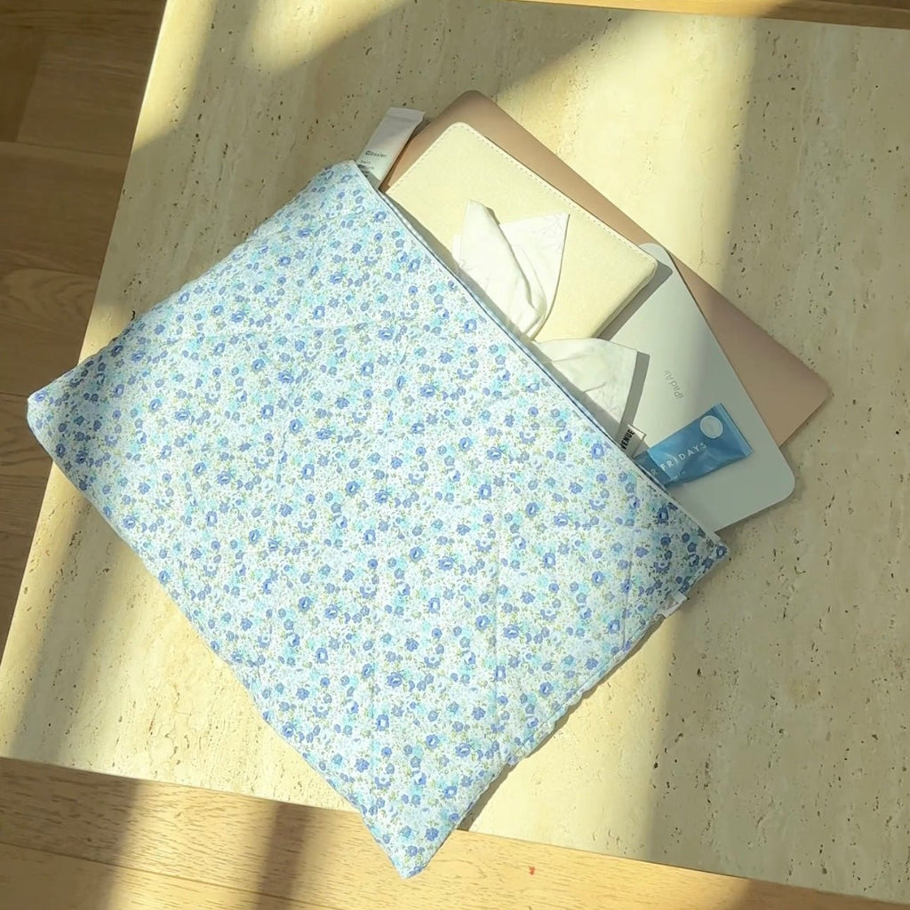 Blue floral zippered pouch folded on a tray with items nearby