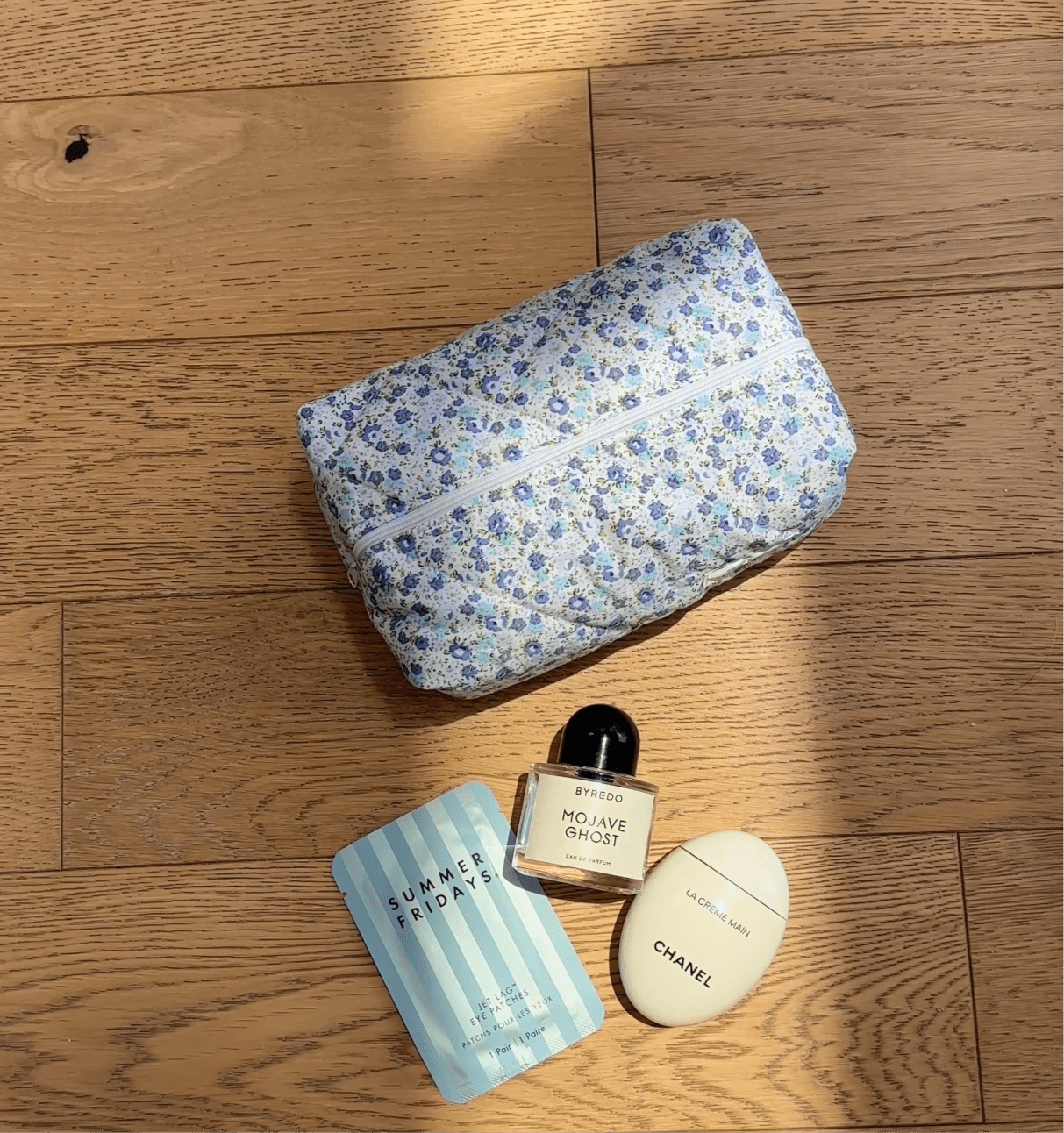Blue floral zippered pouch, closed with top zipper on wood surface