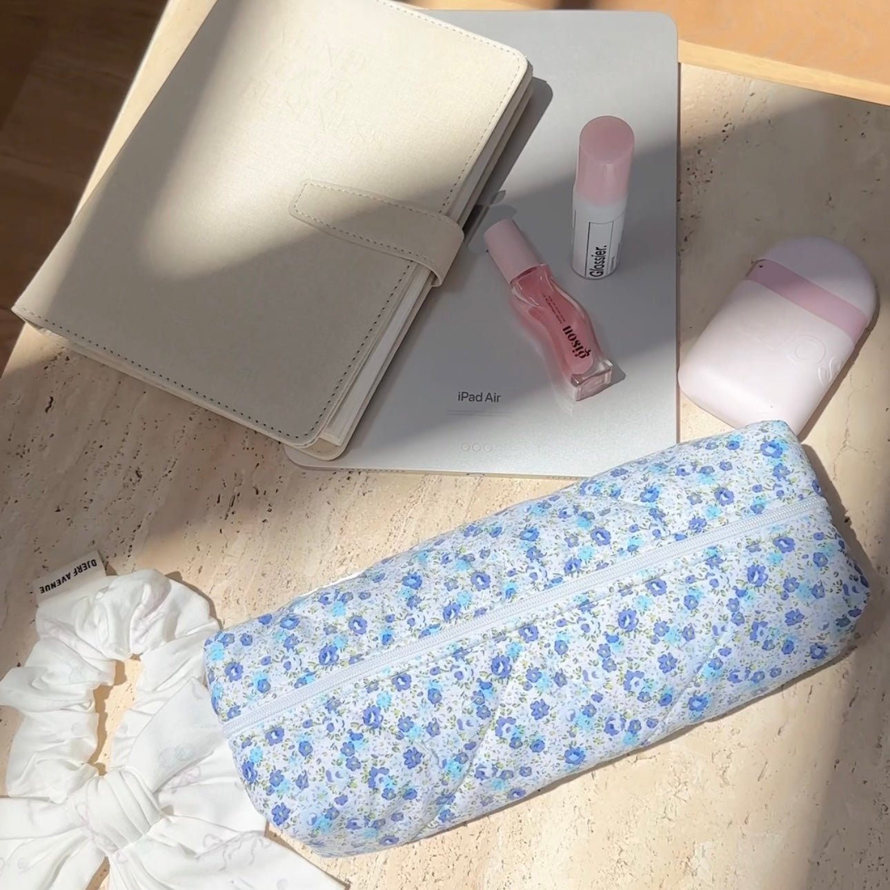Blue floral zippered pouch open with cosmetics bottles visible
