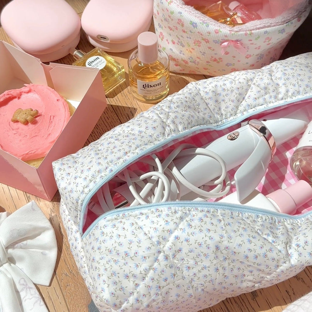 Blue ditsy floral makeup pouch open with light-blue zipper, pink check lining and hair tools