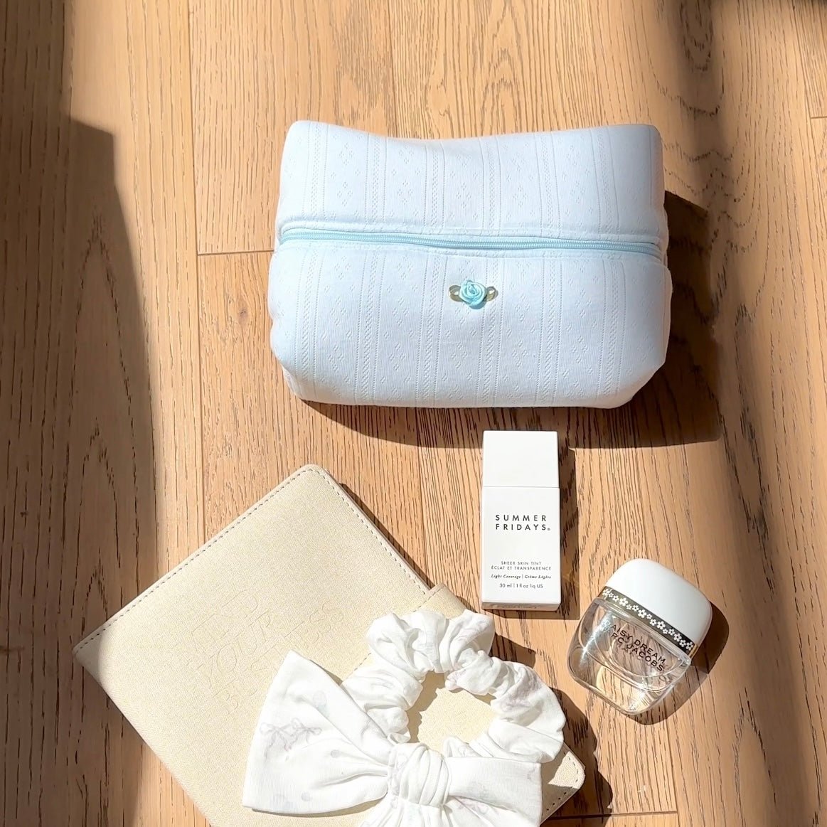 Light blue lace-knit zip pouch, front view with zipper and small rosette pin