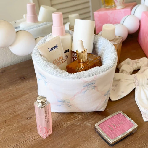 White fabric organizer pouch with blue floral print, holding toiletries bottles and jars