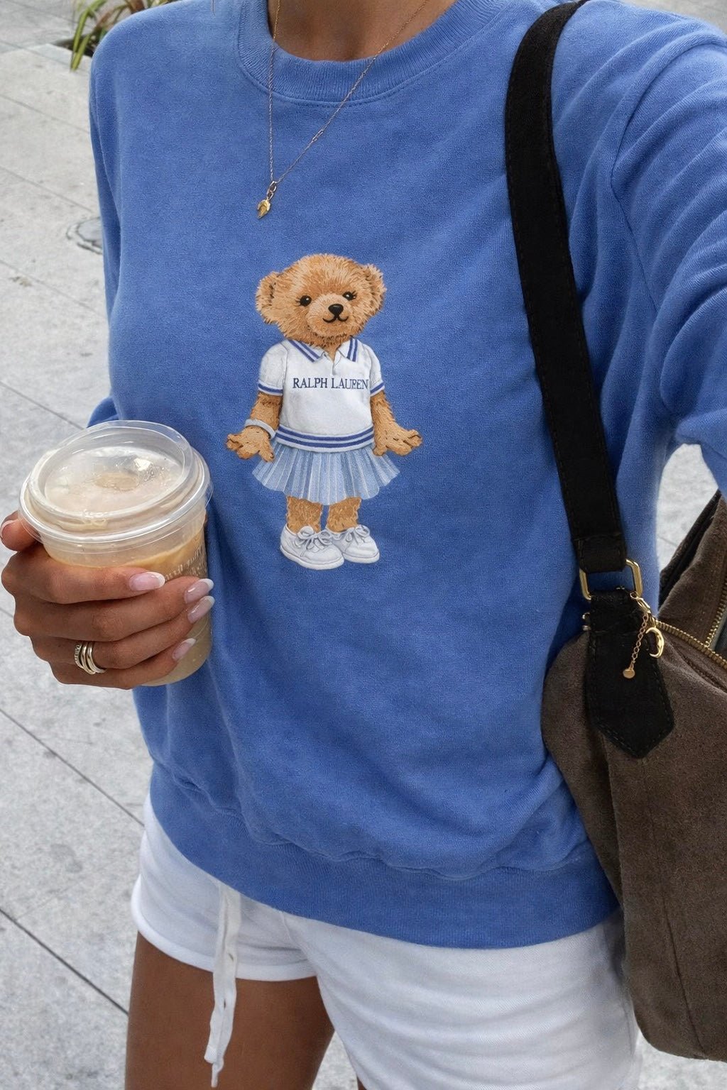 Blue crewneck sweatshirt worn by model, front teddy bear graphic detail