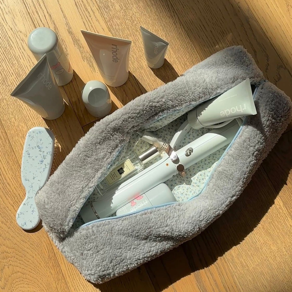 Grey teddy pouch with blue zipper, open top with haircare bottles and tubes inside