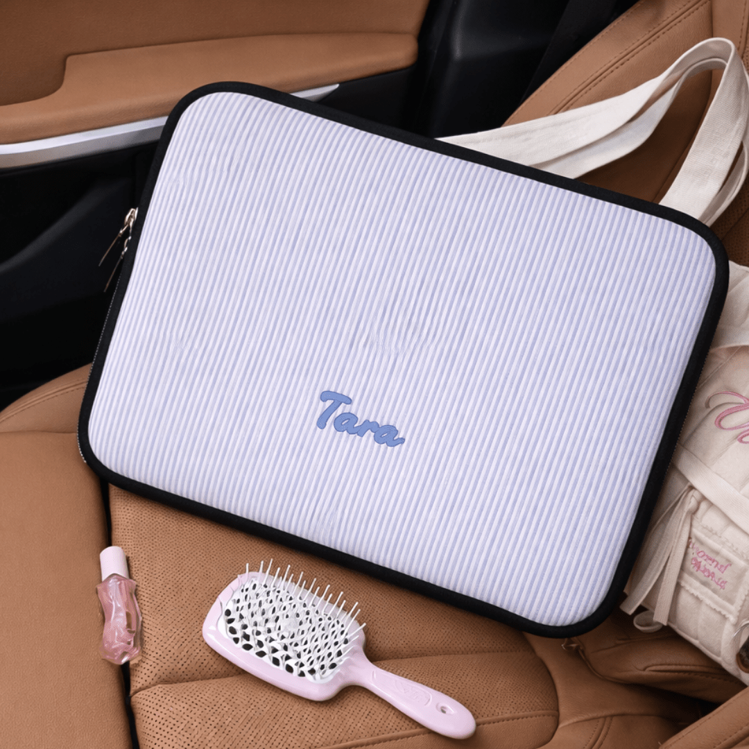 Light blue striped neoprene sleeve with black trim and zipper, personalized “Tara”