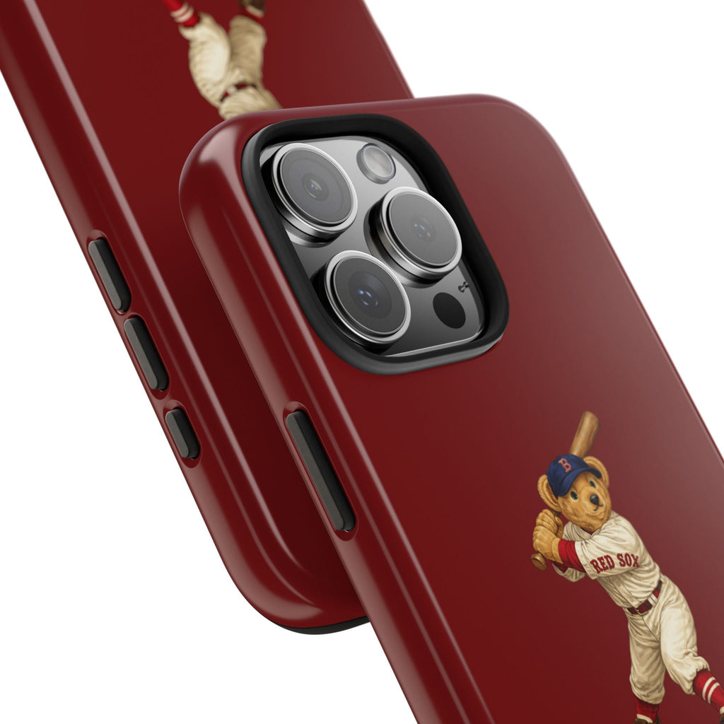 Close-up dark red phone case with teddy bear graphic near corner and camera lenses
