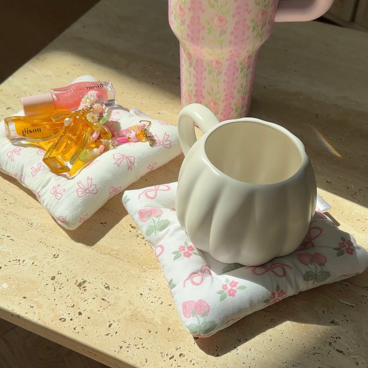 White fabric coaster with pink floral bow print, supporting a white mug