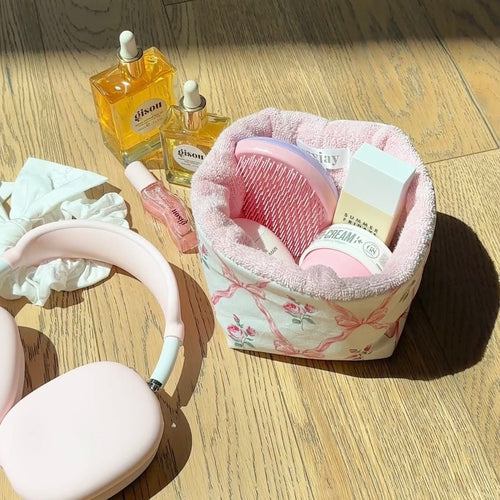 Pink floral storage organizer bin with rounded pink-lined opening on light wood floor