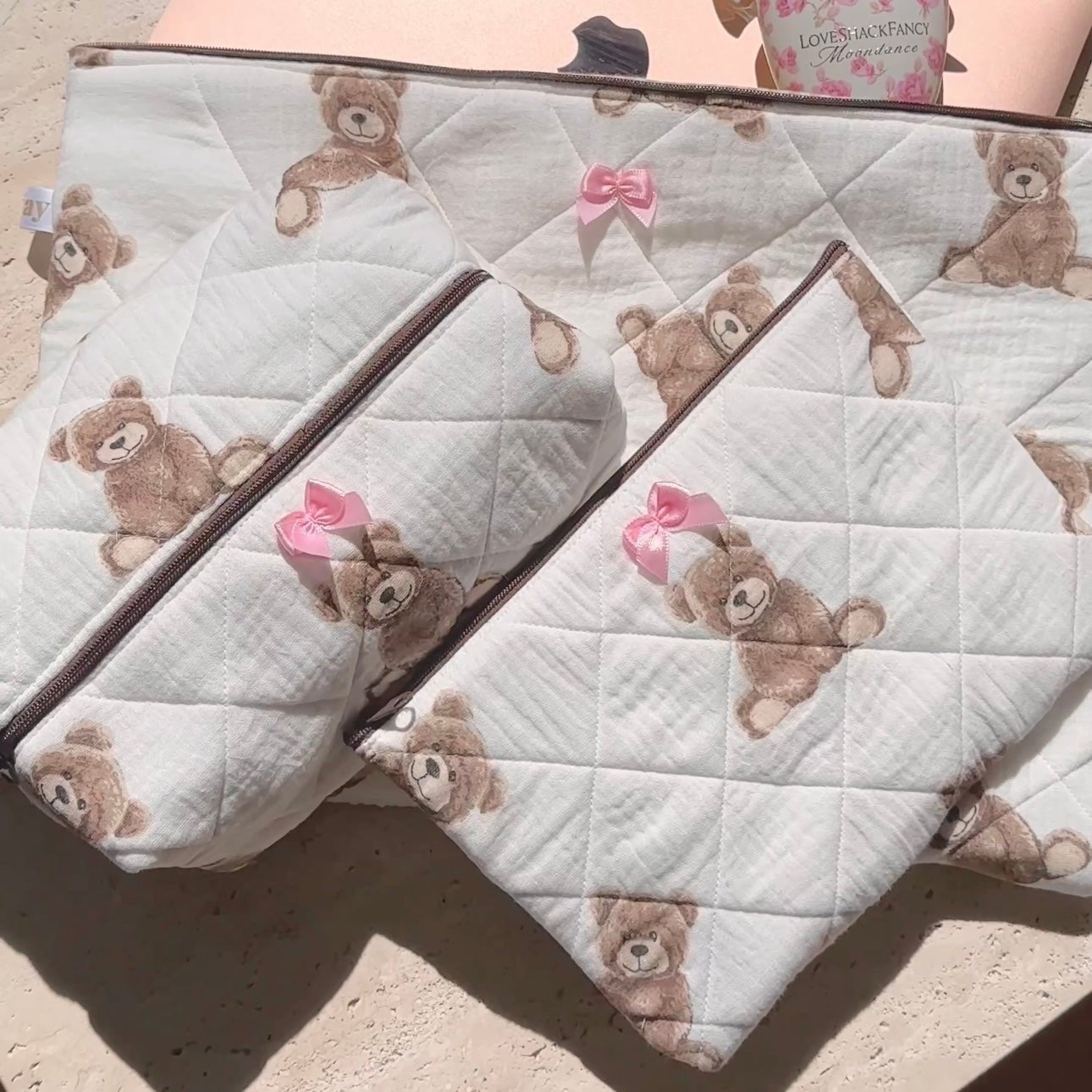 Pair of quilted white teddy bear pouches with pink bow zipper pulls