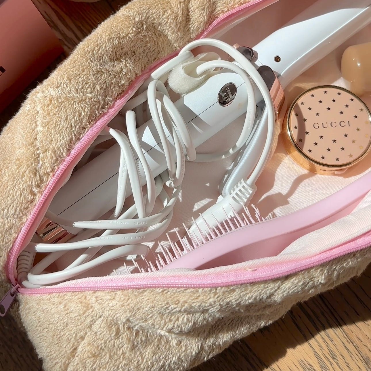 Brown teddy hair tool bag with pink zipper, open to show white styling tools inside