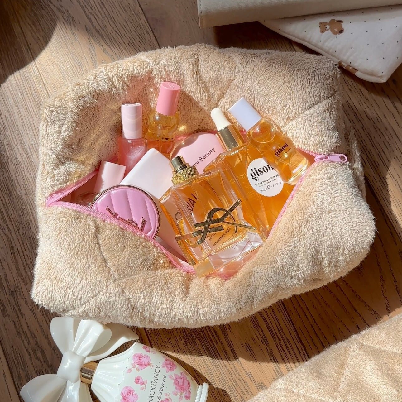 Brown terrycloth pouch with pink zipper and pink trim; rounded shape.